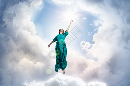 多云天空中的女人穿着绿色长裙的优雅女人云上行走图片