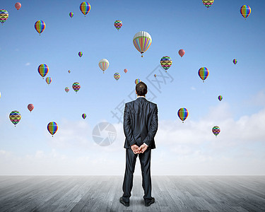 商业上的成功充满希望的商人看着气球天空中飞行的后视镜图片