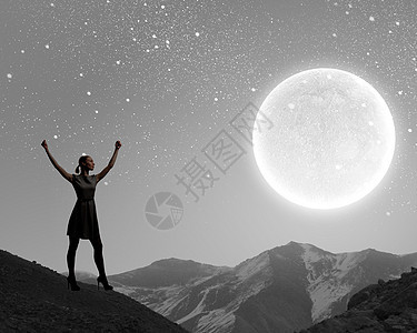 晚上的女人女人着满月的剪影,举手图片
