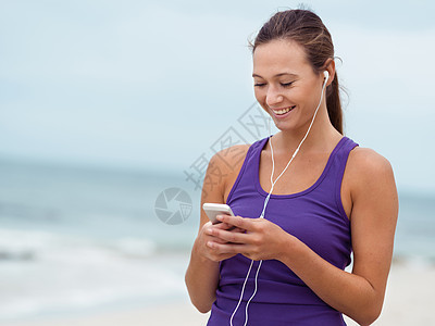海边戴着耳机的运动型轻女人图片