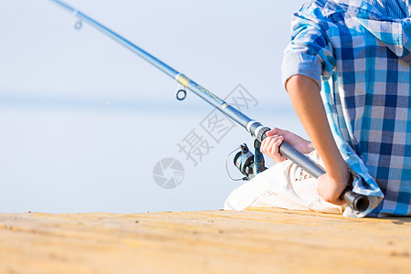 男孩着钓鱼竿码头上钓鱼高清图片