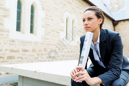 商业女人户外微笑的肖像轻商业女户外坐着思考的肖像图片