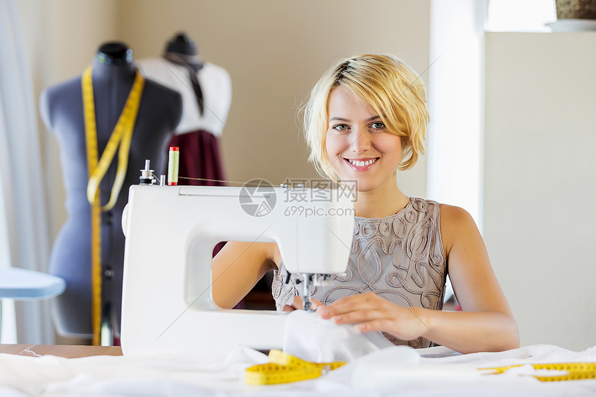 裁缝工作室轻迷人的女裁缝与缝纫机工作图片