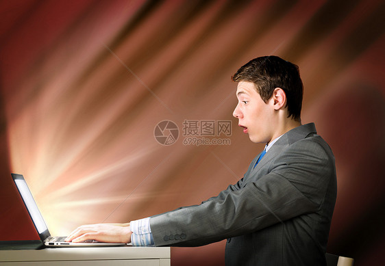 用笔记本电脑的情绪化男人轻人震惊地看着笔记本电脑屏幕图片