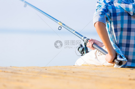 个着鱼竿的男孩的手的特写个男孩的手的特写,他着根钓鱼竿码头上钓鱼图片