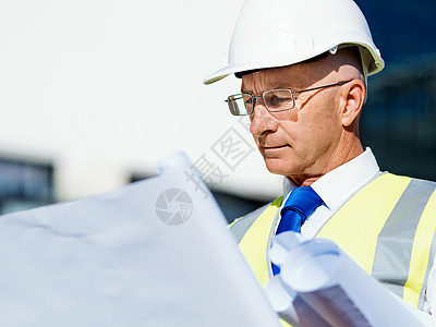 建筑工地的工程师建设者工程师建筑工人施工场景穿着带蓝图的安全背心图片