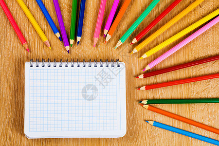 学校固定木制桌子上的彩色铅笔记事本图片