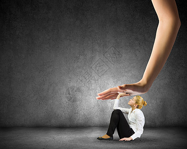 的动力压力轻的女人坐地板上,用巨大的手按住图片