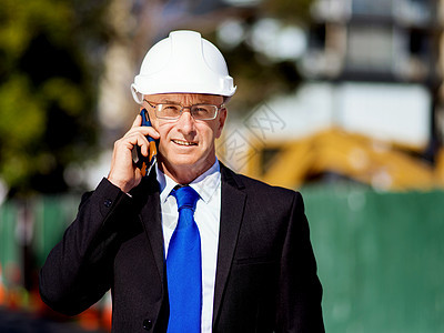 建筑工地的商人施工场景,司机戴着安全帽,带着手机背景图片
