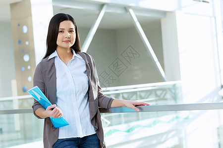 办公楼里魅力的女人轻的黑发女人现代璃内部与文件夹手图片