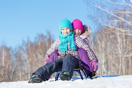 冬天的乐趣两个可爱的女孩美丽的雪冬公园里享受雪橇图片