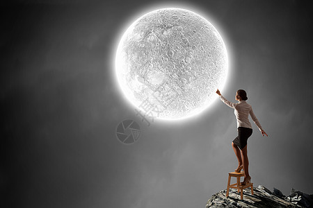 蔚来城女人伸出手来女商人站椅子上,伸手触摸月亮背景