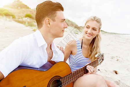 相爱的轻夫妇海滩上弹吉他幸福浪漫的轻夫妇海滩上弹吉他相爱图片