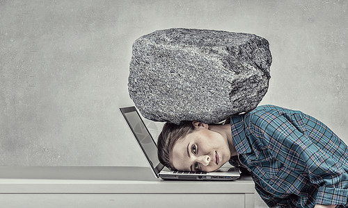 工作的压力下女程序员用沉重的石头压笔记本电脑上图片