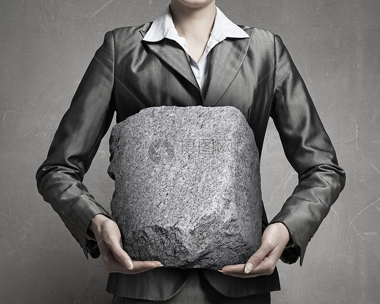 困难的压力下近距离观看女商人着大石头