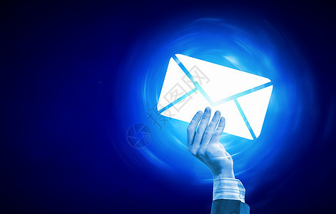 电子邮件人的手着蓝色背景上发光的电子邮件符号图片