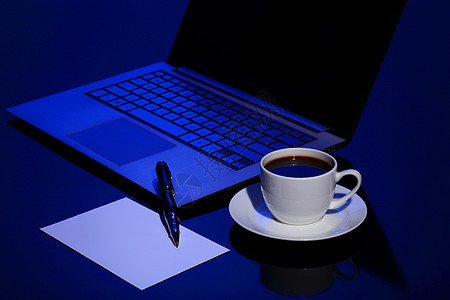 黑色背景下的电脑咖啡笔和纸图片