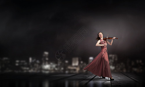 女人拉小提琴轻的女小提琴手,穿着棕色的长裙图片