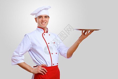厨师的肖像穿着红色围裙的轻男厨师,灰色背景图片