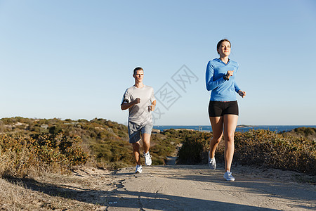 运动跑步者海滩上慢跑,她的搭档锻炼适合女健身模式慢跑沿海洋与她的伴侣图片