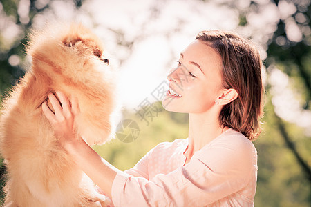 轻的女人夏天的公园狗玩公园带着宠物图片