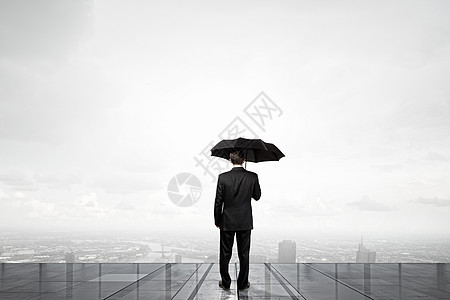 带雨伞的商人带着雨伞的商人的背景看着城市图片