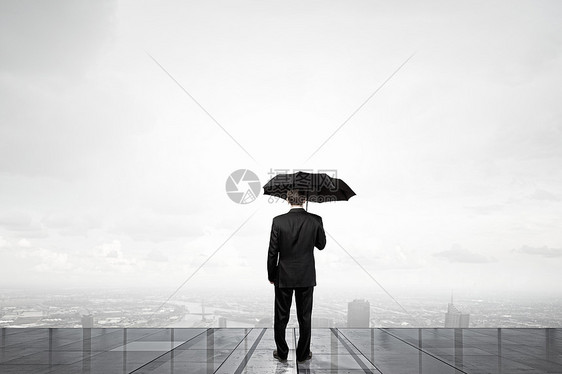 带雨伞的商人带着雨伞的商人的背景看着城市图片