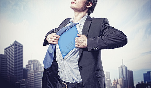 轻的超级英雄商人轻商人的形象,展示超级英雄西装他的衬衫下站城市背景图片