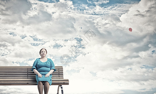 超重问题穿着蓝色连衣裙的中胖女人坐长凳上图片