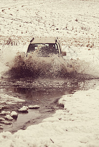 冬季,4x4车辆飞溅的水中行驶图片
