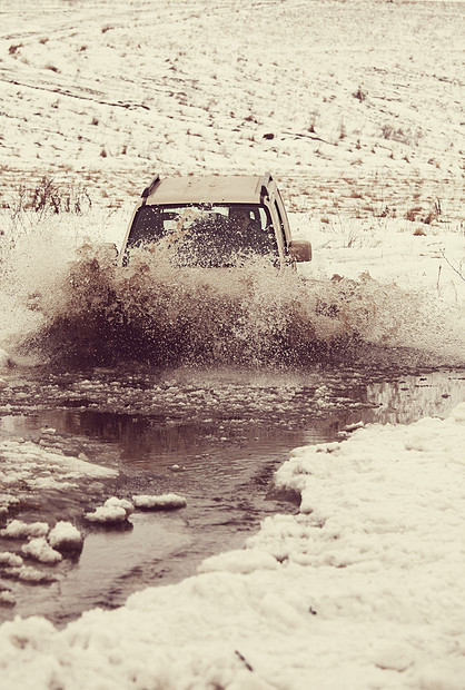 冬季,4x4车辆飞溅的水中行驶图片
