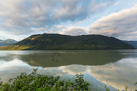 平静的景色加大的山湖旁边,岩石平静的水中反射图片