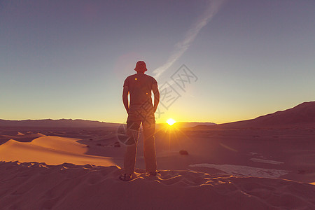 炎热沙漠沙漠里的徒步旅行者日出时间背景