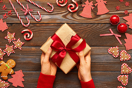 女人着木制背景的诞礼物,自制的姜饼饼干手工装饰图片