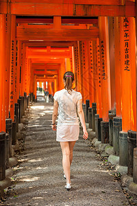 妇女走过木托里大门FushimiInari神社,京都,日本图片