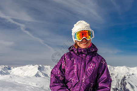 轻女子户外滑雪护目镜与法国阿尔卑斯山覆盖雪的背景梅里贝尔,法国图片