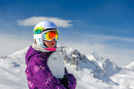 轻的女人,滑雪板户外滑雪护目镜与法国阿尔卑斯山覆盖雪的背景瓦尔迪塞尔,法国图片