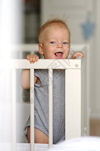 蓝眼睛的小男孩站婴儿床上图片