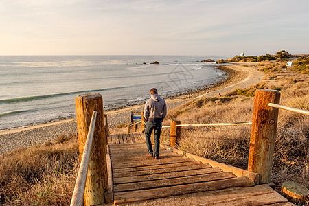 男子步行木板路利奥卡瑞洛州海滩,马里布,加利福尼亚州图片