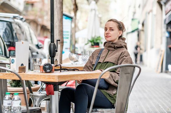 寒冷的春日,城市环境的户外咖啡馆里带着相机的女人巴塞罗那,加泰罗尼亚图片
