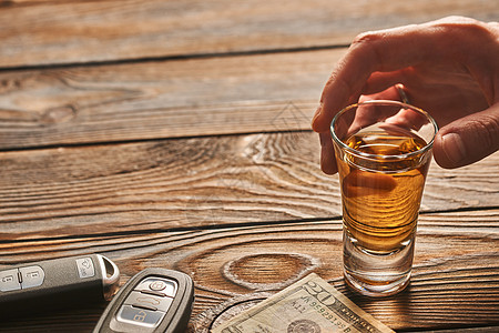 男人的手伸向乡村木桌上的杯龙舌兰酒精饮料汽车钥匙喝酒开车酗酒的安全负责的驾驶理念图片