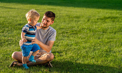 快乐的人孩子草地上玩得很开心父亲儿子公园的绿草地上休息的家庭生活方式场景图片