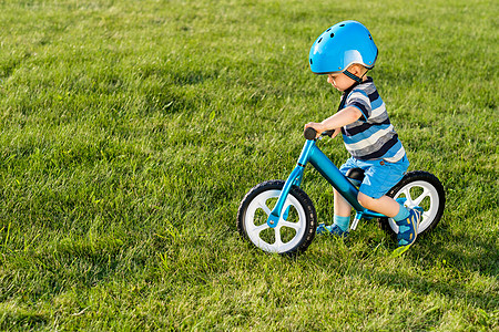 戴头盔的男孩骑蓝色平衡自行车跑步自行车快乐的孩子学花园里的训练自行车上保持平衡健康的学龄前儿童暑期活动孩子图片