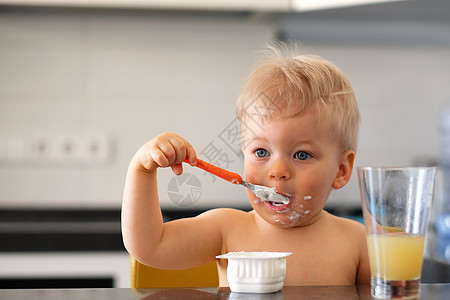可爱的岁小男孩用勺子吃酸奶蹒跚学步的孩子肮脏凌乱的脸图片