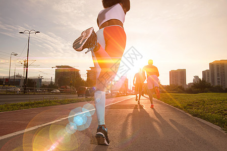 运动跑步慢跑美丽的早晨,太阳升城市的街道上背景