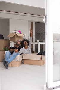 非裔美国夫妇坐个盒子里玩包装材料,搬新家后玩得很开心图片