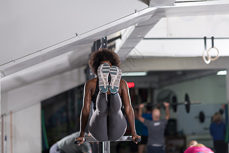 非裔美国运动员妇女水平双杠上锻炼手臂,锻炼三头肌头肌,俯卧撑图片