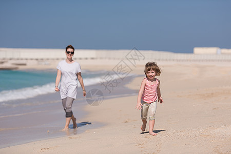 美丽的轻母亲可爱的小女孩正享受异国情调的海滩上沿着海洋旅行度假图片