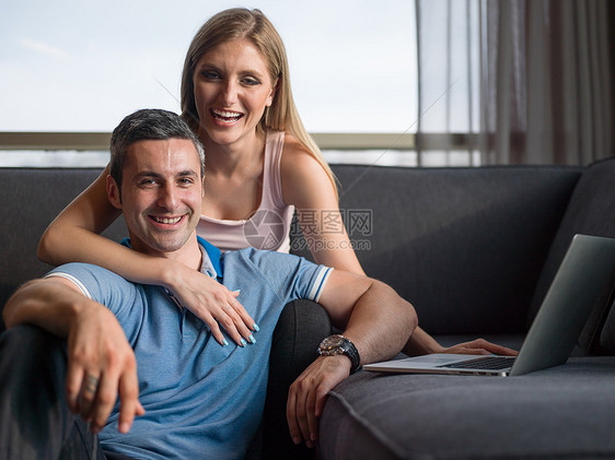 漂亮的夫妇客厅里用笔记本电脑图片