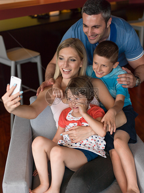 幸福的家庭坐沙发上,用手机家里打视频电话图片